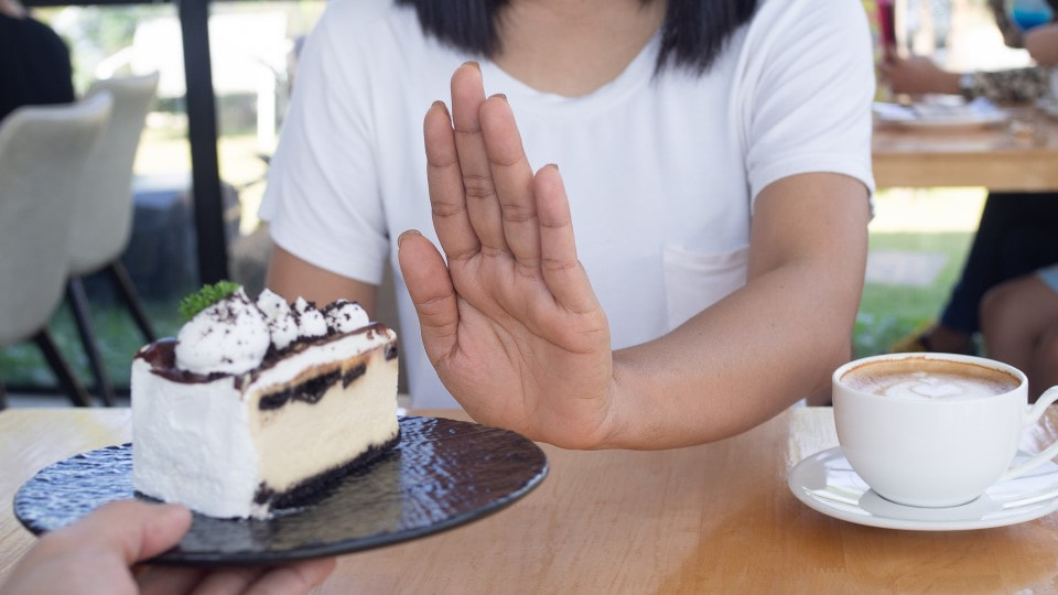 A woman declines a slice of cake